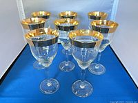 Front view showing all eight gold-rim wine glasses