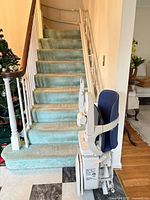 Full view of stairlift at base of staircase showing chair, rail and fold-up components