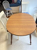 Top view of wooden dining table with two slat-back chairs and spindle chair partly visible