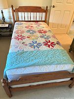 Twin bed frame with mattress and quilt, honey brown finish, spindle headboard and footboard shown