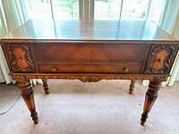 Front view of mahogany drop-front secretary desk showing full-width drawer and carved apron