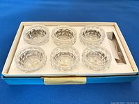 Box containing six pressed glass salt cellars with spoons compartment visible
