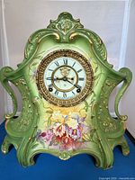Front view showing entire green porcelain clock with floral decoration and dial