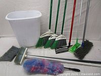 Group shot showing wastebasket, three angled brooms, push broom, flat mop, chenille mop and duster