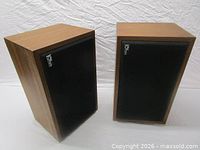Front angled view of both Ohm bookshelf speakers showing grilles and veneer finish