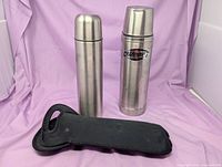 Two stainless steel thermoses and black neoprene sleeve