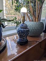 Front view of blue and white porcelain ginger jar lamp with bulb on wood base