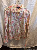 Front view of floral cotton blouse on hanger