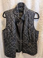 Front view of navy polka dot quilted vest on hanger