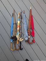 Six closed umbrellas side-by-side showing handles and fabric patterns