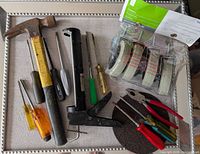 overview of hammer, screwdrivers, caulk gun, caster package, pliers, discs
