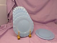 Six light blue milk glass plates displayed upright and one flat showing size and color