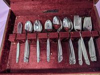 Open wooden canteen showing stainless steel spoons and forks in velvet slots