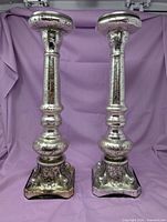 full view of both mercury glass candlesticks standing upright