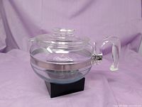 Full view of clear glass Pyrex teapot with lid and handle