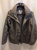 Front view of grey Columbia women’s jacket hanging, showing overall design, pockets, sleeves, zip-off hood.