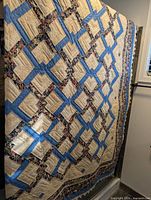 Full view of quilt showing tan, blue lattice and floral border