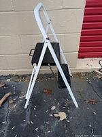 Side view of folded 2-step white metal stool with black steps