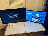 Two televisions on table; Samsung left, ONN Roku right powered on