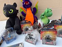 Plush dragons, sealed Toothless figures, Jasmine figurine visible