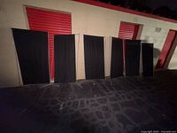 Five of the seven black fabric panels standing outdoors showing overall design and size
