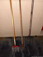 Three long-handled tools leaning on wall
