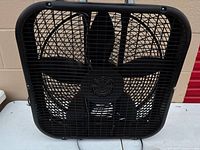 Front view of black Lasko box fan showing grille and blades