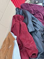 All four coats laid out: brown corduroy, red, black, purple