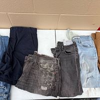 Six folded pairs of jeans on table showing colours and wear