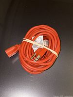 Coiled orange extension cord showing both male and female ends