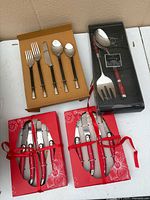 Assortment showing five-piece place setting, red steak knife sets and red-handled serving set