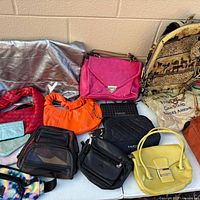 Overview of multiple purses, backpack, tote on table