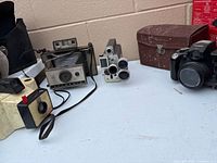 All four cameras, flash unit and case on table