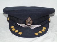 Front view of navy captain’s hat showing pilot wings badge, maple leaf embroidery, mesh band and brass buttons