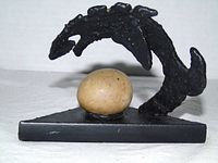 Front left view of cast iron sculpture showing arched form and stone on triangular base