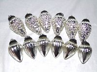 Twelve silver ornaments laid out, upper row grape clusters, lower row ribbed teardrops