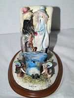 Front view of ceramic figurine showing couple in antique car on wooden base