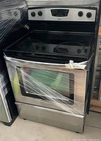 Front view of Amana stainless steel electric range wrapped in plastic