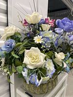 Front view of faux flower arrangement in green ribbed ceramic pot