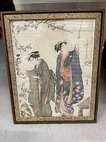 Front view of framed Japanese print showing two women in kimonos and floral mat