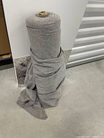 Full view of grey fabric roll standing upright