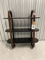 Front view of Umbra Bellwood 3-Tier shelf showing three black shelves and curved walnut supports