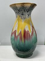 Front view of ceramic vase showing multicolor drip glaze and gold-tone rim