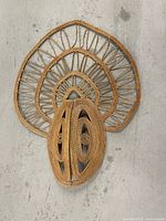 Full view of woven rattan mask hanging on wall