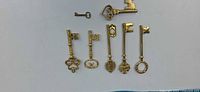 Seven gold-tone skeleton keys laid out for size and style reference