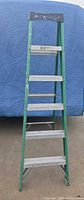 Front view of folded 6 ft Louisville FS4006 ladder showing aluminum steps and top cap.