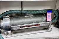 Full view of canister vacuum on shelf with hose attached