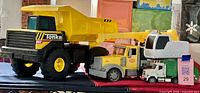 Full view of three toy vehicles: Tonka dump, crane truck, refuse truck