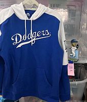 Front view of Dodgers hoodie on hanger, bobblehead nearby