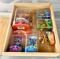 Top-down view of six sealed Skylanders figures arranged in wooden box